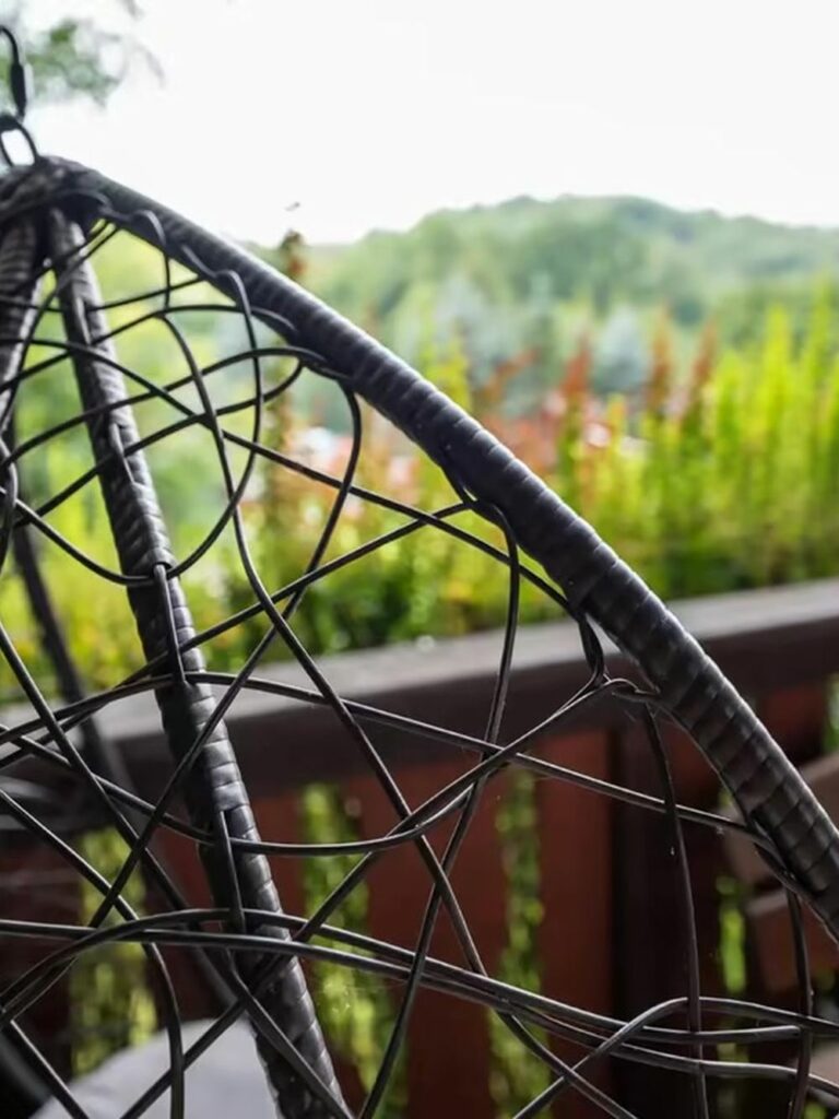 Wiszący fotel na tarasie domku z widokiem na wzgórza